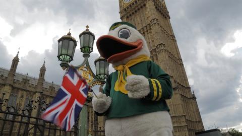 The Duck mascot holding a UK flag in front of the Big Ben tower