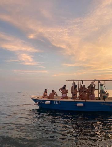 Ten people enjoying the sunset on a small boat at sea.