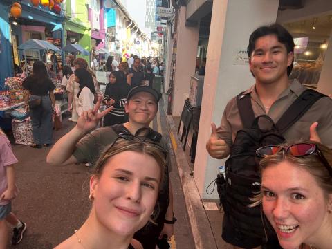 Logan and three other people pose for a picture in a crowded alley