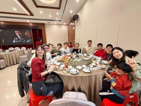 people sit around a large circle table, dressed in red and celebrating Chinese New Year