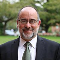 Profile image of Dennis Galvan, man wearing glasses and dressed in a suite
