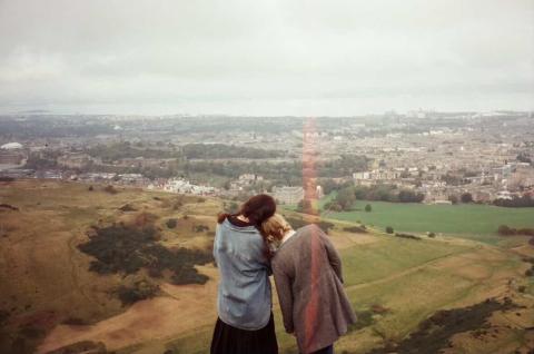 Film photo of one student resting their head on another student's shoulder in the English countryside