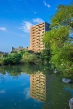The National Taiwan University Biotechnology building stands over a reflective lake.