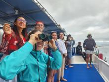 Students stand on a boat looking out into the ocean