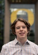 A young man stands in front of Lillis business complex