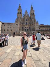 A young woman stands in front of an ornate building