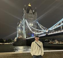 A young man stands in front of London's Tower Bridge