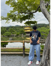 A young man stands in front of a Japanese temple