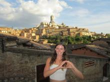 A young woman stands by a Siena skyline