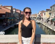 A young woman stands on a bridge in Italy