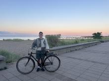 Smiling college-aged male with bicycle posing during a sunset.
