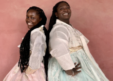 Two college students posing back-to-back wearing traditional Korean dresses.