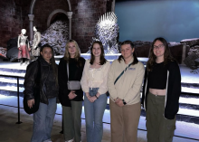 Five college students standing in front of a "Game of Thrones" set. 