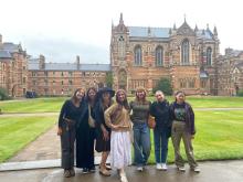 Group of seven college students posing in front of historic building.
