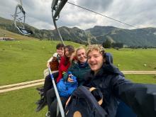 Four college students sitting on a skylift in the Dolomite Mountains in Italy. 