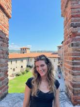 Person smiling inside the Castelvecchio in Verona with scenic views of historic buildings and skyline in the background.