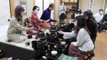 A group of people participating in a traditional Japanese tea ceremony in a tatami-matted room.