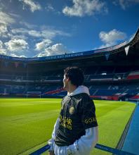 Person standing on the field at Parc des Princes stadium, home of Paris Saint-Germain, looking around under a clear sky.