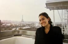 A person smiling, seated on the Ferris wheel with the Eiffel Tower and Paris skyline in the background.