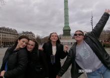 Four friends posing joyfully in front of the Place Vendôme Column in Paris.