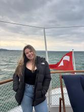 Person smiling on a boat with the Turkish flag visible in the background.