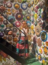 A person exploring a vibrant shop decorated with colorful, assorted sun and moon face masks on the walls.