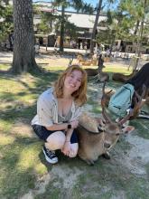 A college-aged girl posing next to a deer in Japan's deer park. 