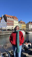 College-aged female smiling in front of line of colorful houses along the waterfront in Denmark.
