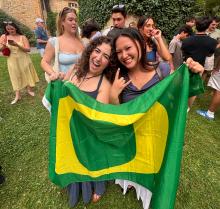 Two people holding a University of Oregon flag on a field of grass. 