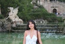 College-aged woman smiling in front of fountain. 