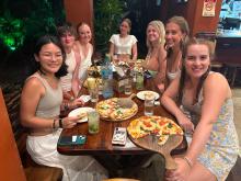 Lane and 6 friends sitting at a table eating pizza