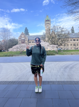 Keke stands in front of a clock tower, holding up a peace sign