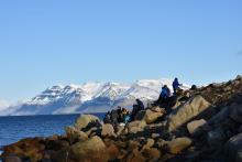 students climbing on rocks with mountains in the distance