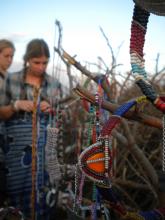 Two people standing in the background looking at bracelets on a tree