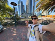 Calvin taking a selfie in sunny Melbourne with skyscrapers in the background.