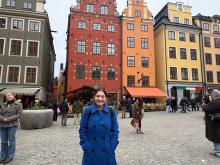 Student smiling in front colorful buildings in Stortorget, Sweden