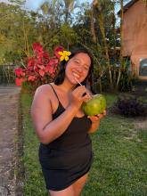 Valeria smiling on the grass in Costa Rica while drinking from a coconut.