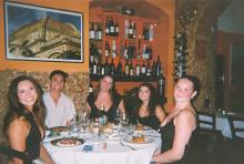 Film photo of five students gathered around a table in Italy enjoying dinner and wine