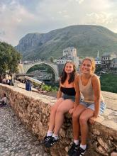 Maya smiling with another student on a cobblestone bridge in Europe