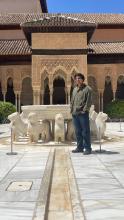 Kunal smiling by a courtyard with lion statues in Spain