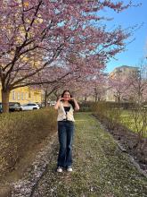 Ava smiling under a cherry blossom tree in Stockholm, Sweden