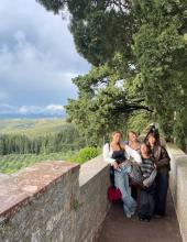 Gisele with three friends smiling on a walk in Italy under a shaded tree