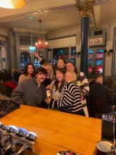 Group of seven GEO students smiling at a pub in London