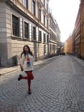 Ava smiling in the cobblestone streets of Stockholm, posing with one leg up 