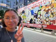 a uo student posing next to a mural of Japanese art 