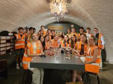 A group of UO students sitting and standing around a table wearing orange safety vests