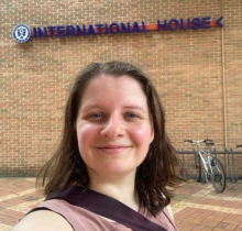 A UO student standing in front of a brick wall with blue text