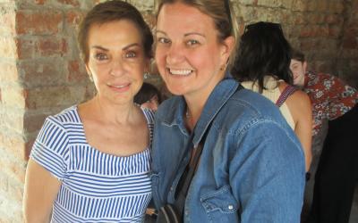 Two women stand in front of a brick wall