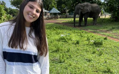 A young woman stands near an elephant