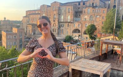 A young woman stands on a balcony in Siena, Italy